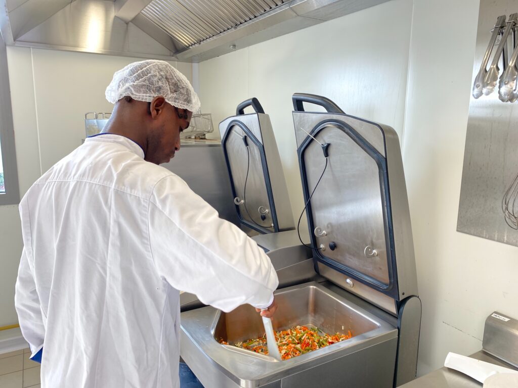 Une personne de l'équipe de cuisine de la Maison de Nicodème en train de faire revenir des légumes